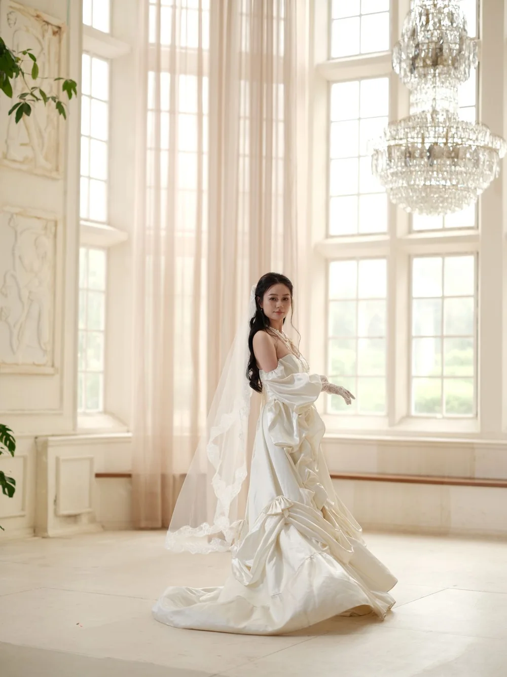 Bride in an ivory gown in a sunlit ballroom