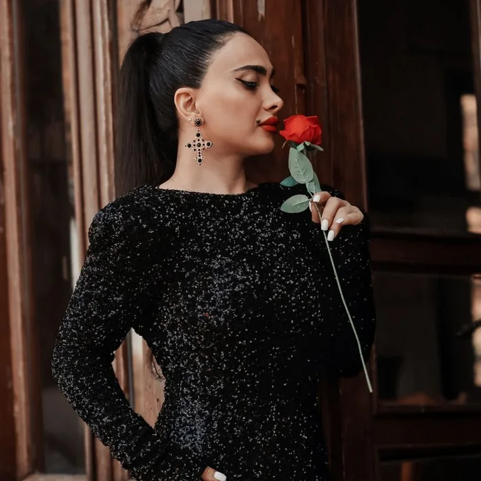 Woman in a black sequinned dress holding a rose
